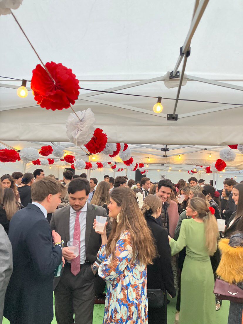 Interior de carpa plegable decorada con pompones rojos y blancos y guirnaldas de luz