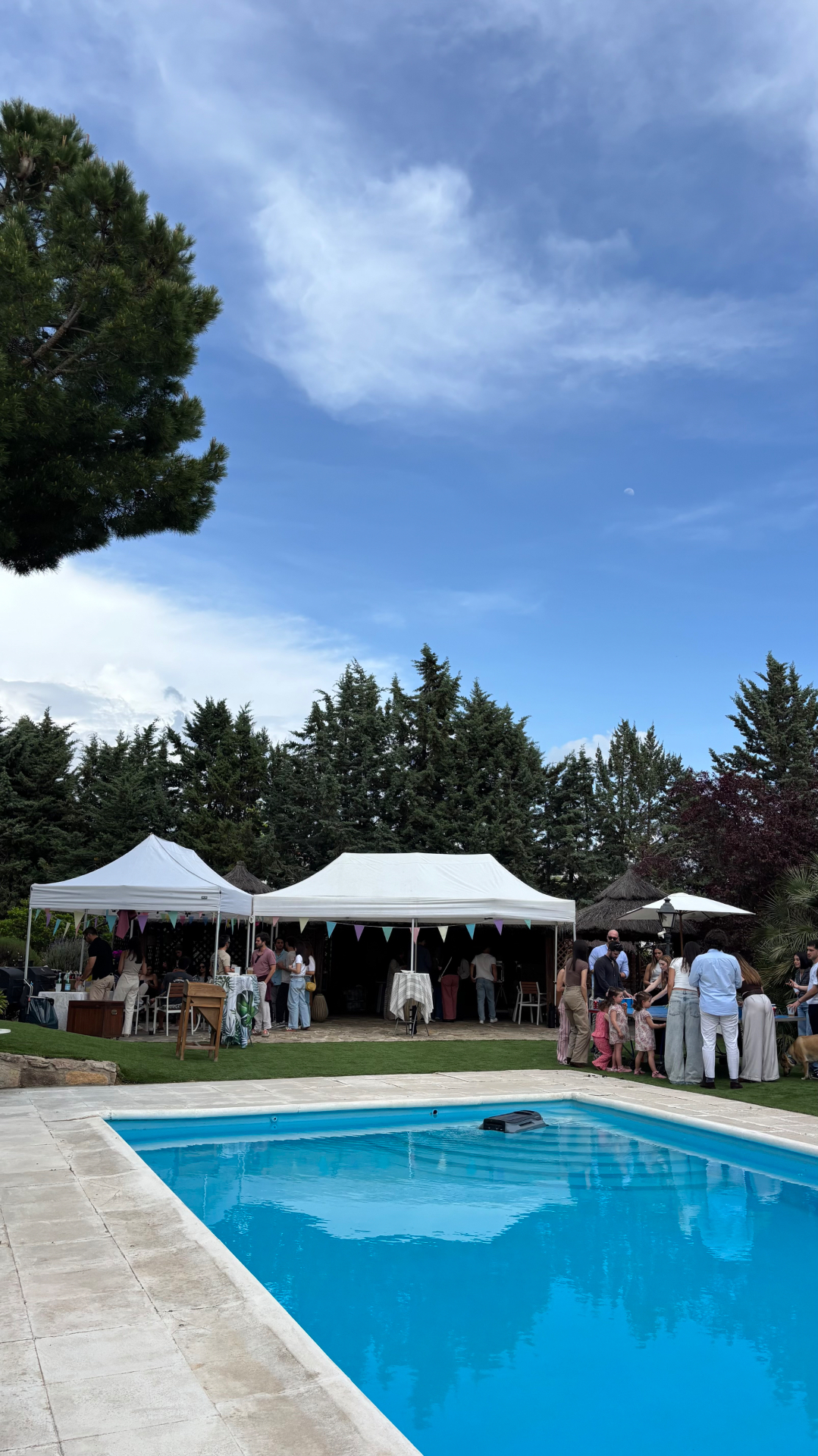 Carpas plegables blancas unidas en un jardín con piscina, celebración de comunión